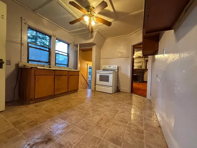 a view of a kitchen with a stove cabinets a ceiling fan and wooden floor