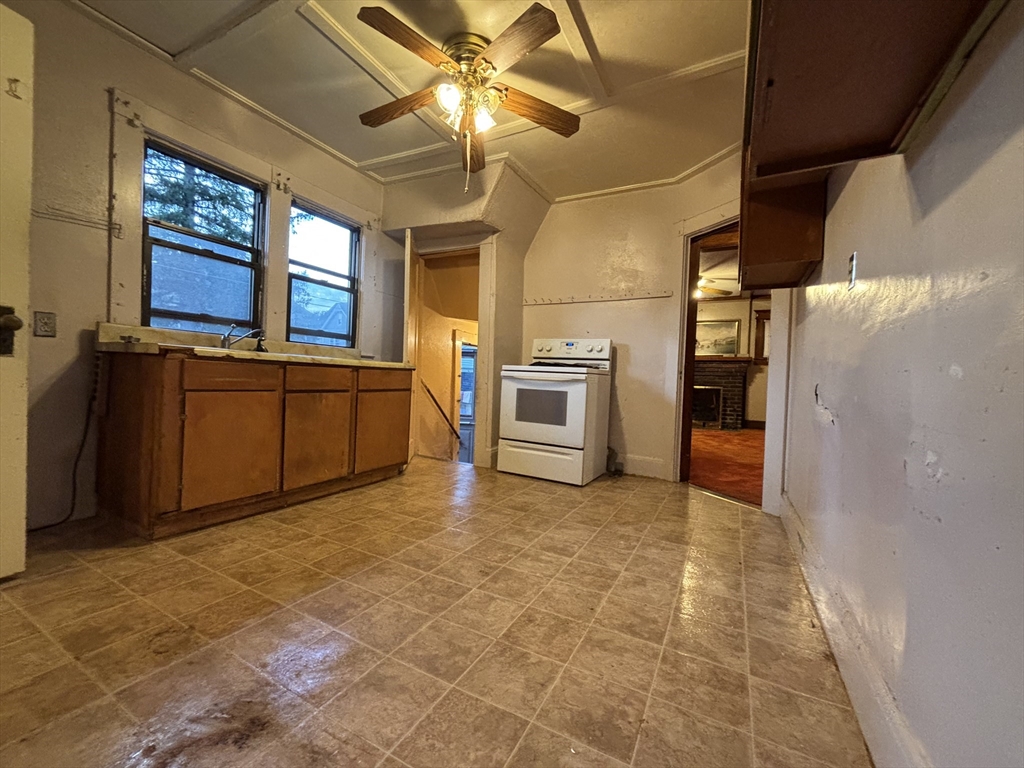 88 Dunmoreland Street Springfield, MA 01109 - Photo 6 of 29 a view of a kitchen with a stove cabinets a ceiling fan and wooden floor