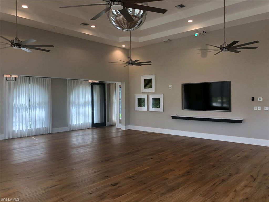 5423 Useppa Drive Ave Maria, FL 34142 - Photo 29 of 35 an empty room with wooden floor a ceiling fan a fireplace and windows