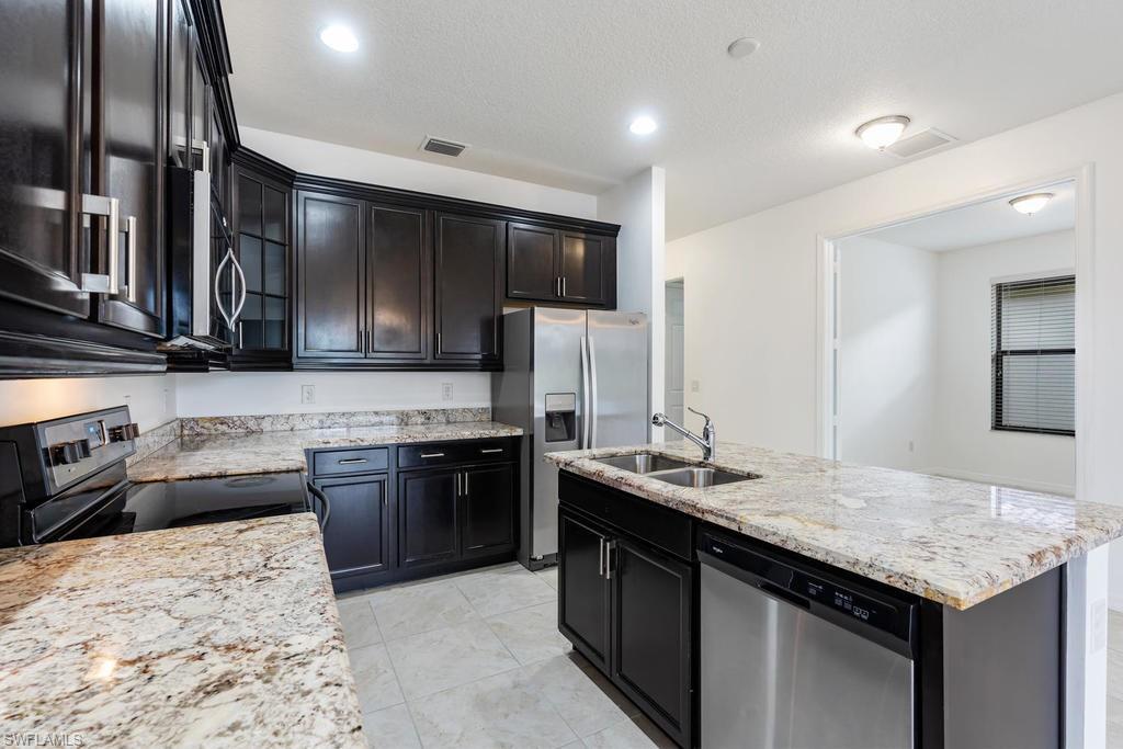 5423 Useppa Drive Ave Maria, FL 34142 - Photo 4 of 35 a kitchen with stainless steel appliances kitchen island granite countertop a sink stove and refrigerator