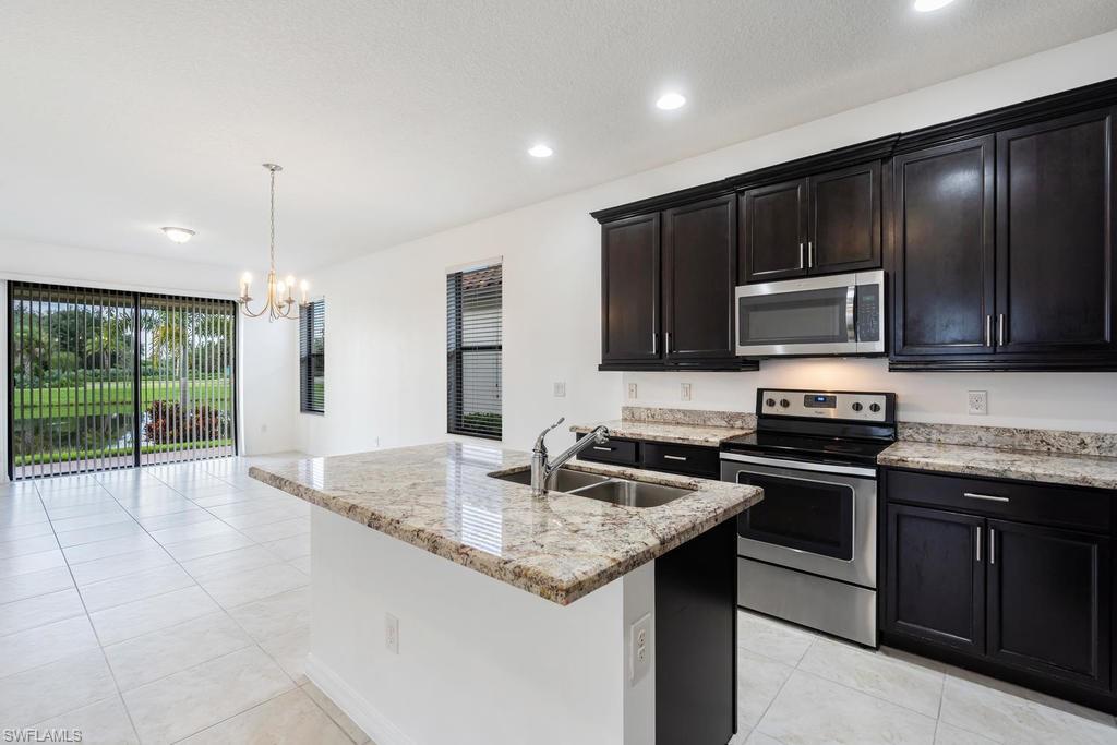 5423 Useppa Drive Ave Maria, FL 34142 - Photo 6 of 35 a kitchen with granite countertop stainless steel appliances and wooden cabinets