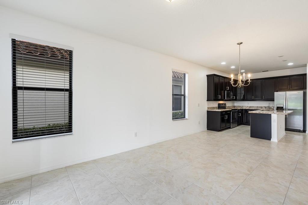 5423 Useppa Drive Ave Maria, FL 34142 - Photo 9 of 35 a view of kitchen with kitchen island stainless steel appliances a sink cabinets and a counter top space