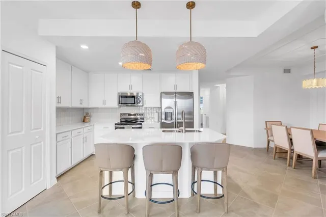 a kitchen with stainless steel appliances granite countertop a sink a stove a dining table and chairs