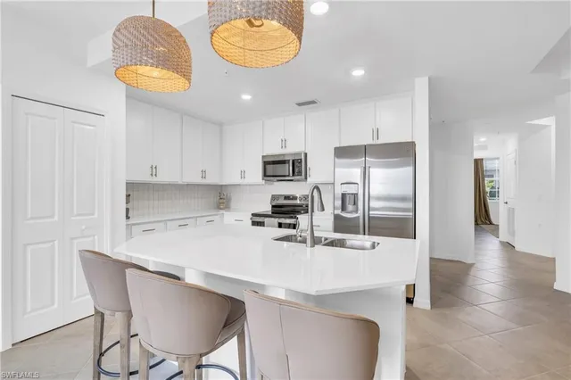 a kitchen with stainless steel appliances granite countertop a sink a stove a refrigerator and a dining table with wooden floor