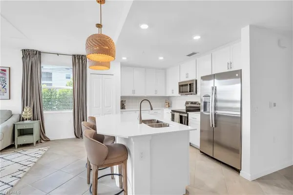 a kitchen with stainless steel appliances granite countertop a refrigerator a stove a sink dishwasher a dining table and chairs with wooden floor