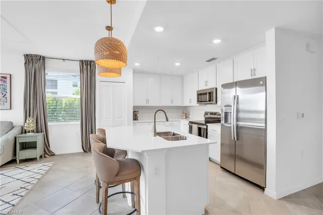 a kitchen with stainless steel appliances granite countertop a refrigerator a stove a sink dishwasher a dining table and chairs with wooden floor