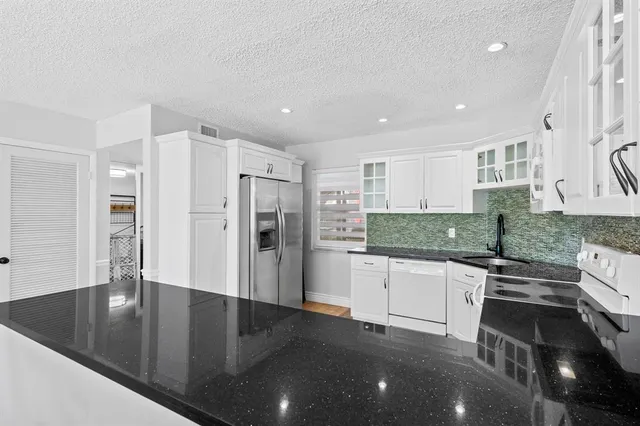 a kitchen with granite countertop a stove sink and cabinets