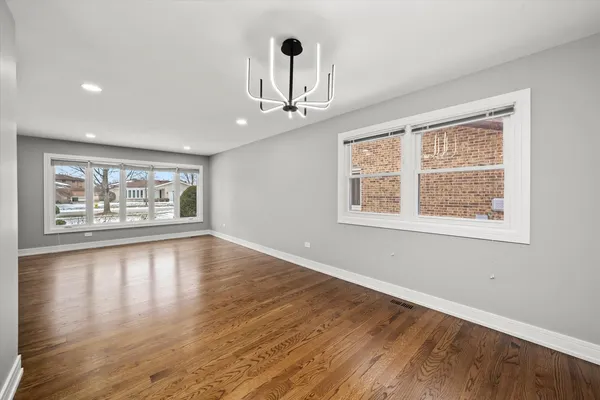 a view of an empty room with window and wooden floor