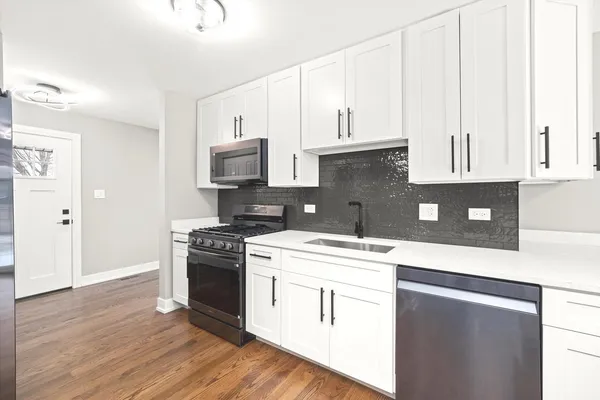 a kitchen with stainless steel appliances granite countertop a stove a sink and white cabinets