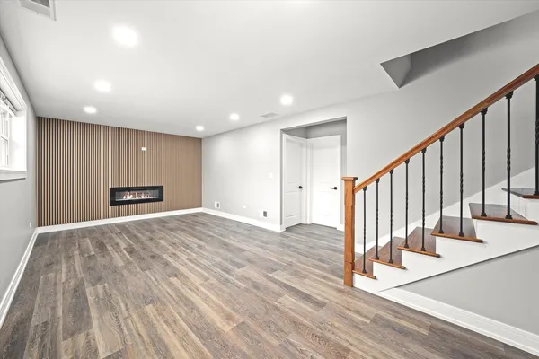 a view of an empty room with wooden floor and stairs