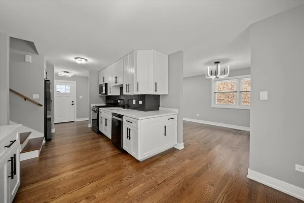 a kitchen with granite countertop a stove a sink dishwasher and a refrigerator with wooden floor