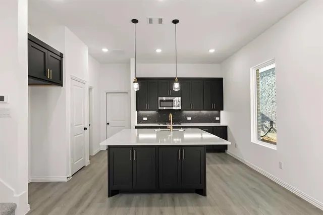 a large kitchen with a center island wooden floor stainless steel appliances and a window
