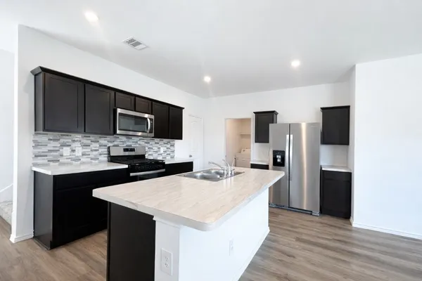 a kitchen with a sink a counter top space stainless steel appliances and cabinets