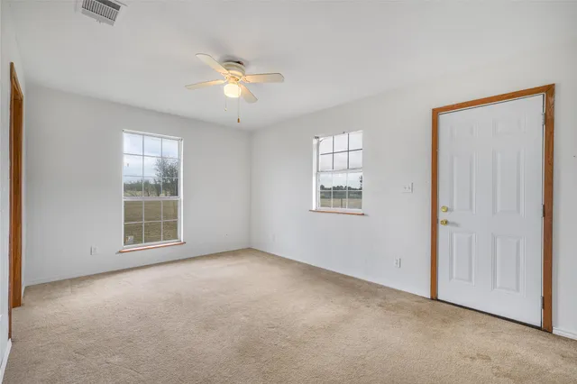 an empty room with windows and fan
