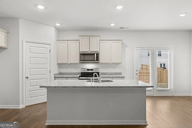 a large kitchen with stainless steel appliances granite countertop a stove a sink and a refrigerator
