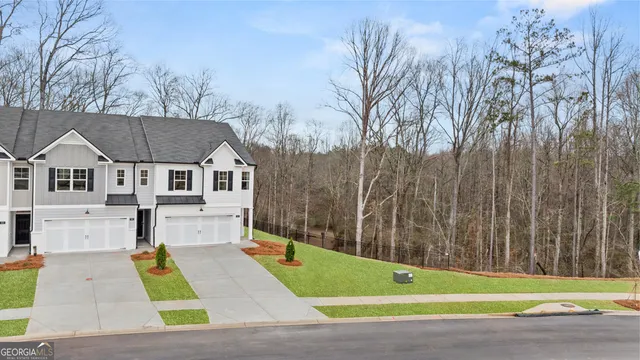 a view of a white house with a small yard and large trees