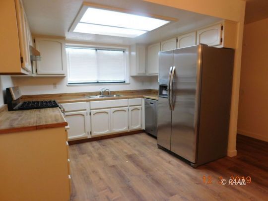 613 Ginger Avenue Ridgecrest, CA 93555 - Photo 2 of 9 a kitchen with stainless steel appliances granite countertop a refrigerator a sink a stove and white cabinets