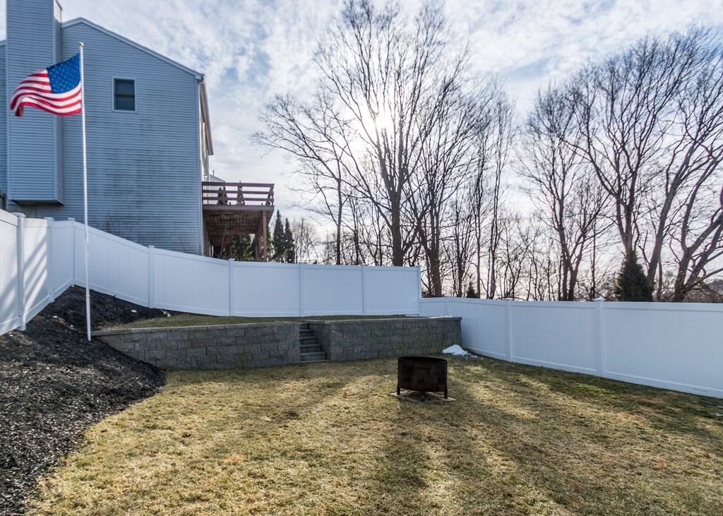 89 Pine Hill Circle Waltham, MA 02451 - Photo 28 of 32 a backyard of a house with wooden fence and large trees