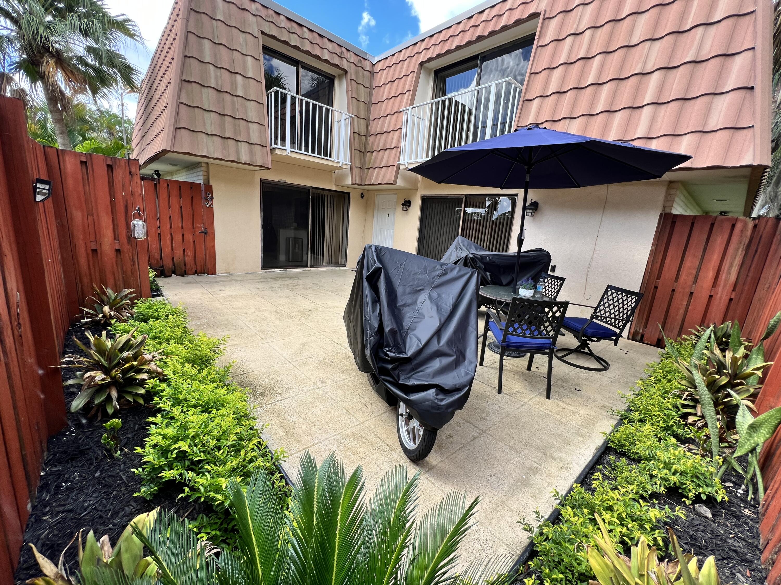 802 Blue Ridge Circle West Palm Beach, FL 33409 - Photo 7 of 37 a view of a front of a house with table and chairs under an umbrella