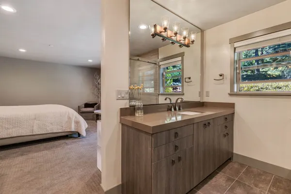a en suite bathroom with a granite countertop sink a large mirror and a shower