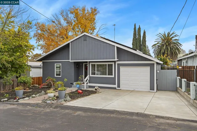 a backyard of a house with table and chairs under an umbrella
