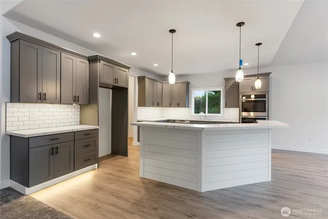 a large kitchen with granite countertop a sink a counter top space stainless steel appliances and cabinets