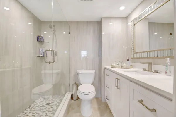 a bathroom with a granite countertop sink a toilet and shower