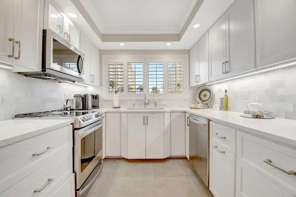 a kitchen with stainless steel appliances granite countertop white cabinets a sink and a stove