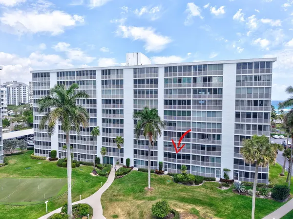 a view of front of residential apartment building with a yard
