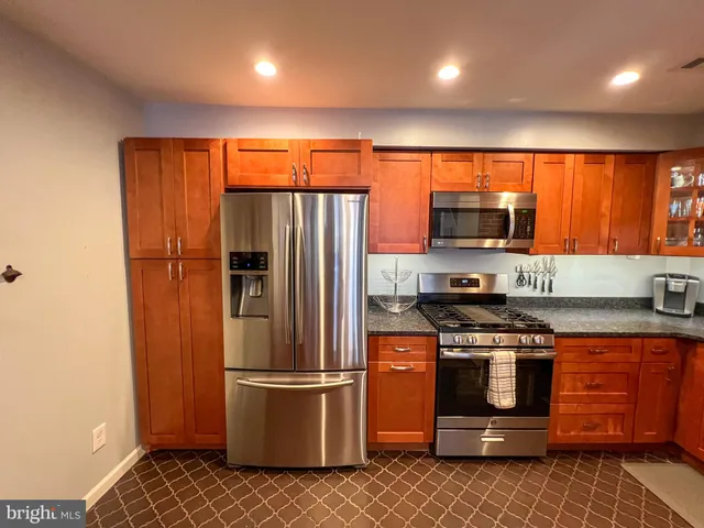 a kitchen with stainless steel appliances granite countertop a refrigerator a stove a sink and a microwave