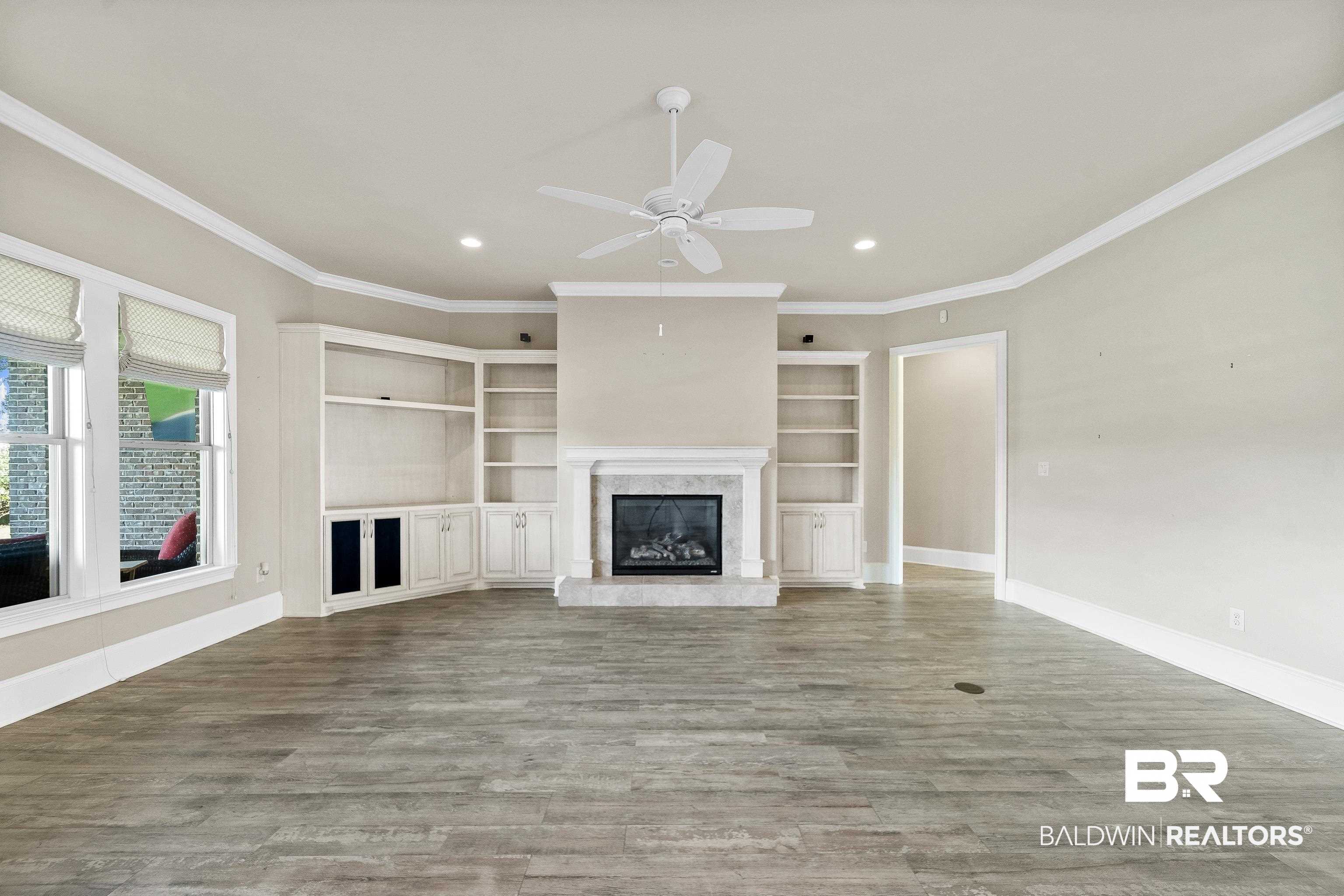 17663 Burwick Loop Fairhope, AL 36532 - Photo 11 of 41 Unfurnished living room featuring a premium fireplace, ornamental molding, ceiling fan, and hardwood / wood-style floors