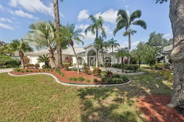 a view of a house with a yard and palm trees
