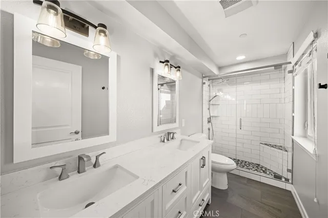 a bathroom with a double vanity sink toilet mirror and shower