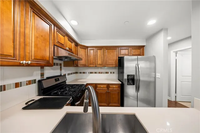 a kitchen with stainless steel appliances granite countertop a refrigerator and a sink