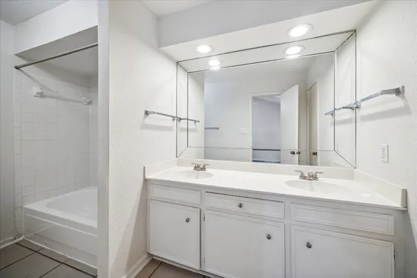 a bathroom with a double vanity sink a mirror and a bathtub