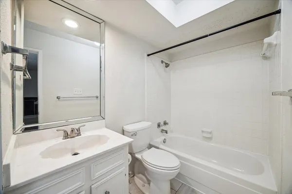 a bathroom with a bathtub shower sink vanity mirror and toilet
