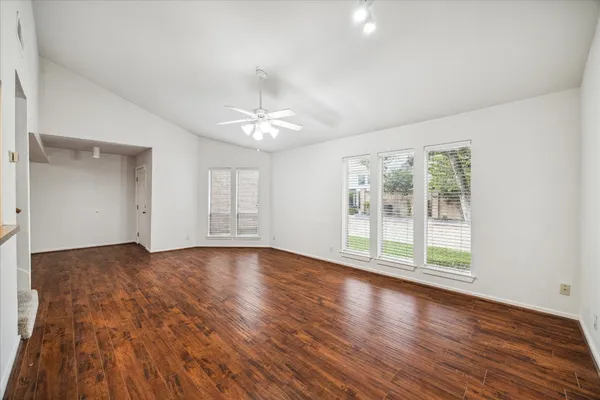 a view of an empty room with wooden floor and a window