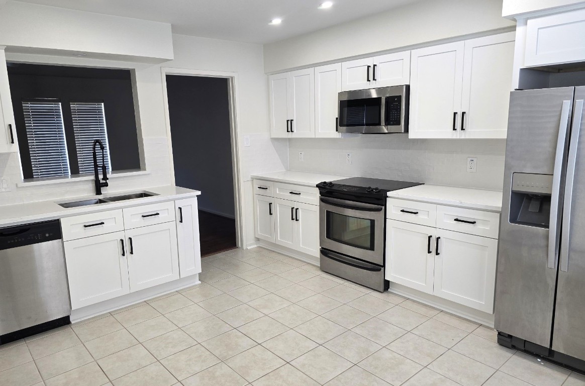 1864 South Gessner Road Houston, TX 77063 - Photo 6 of 17 a kitchen with white cabinets and stainless steel appliances