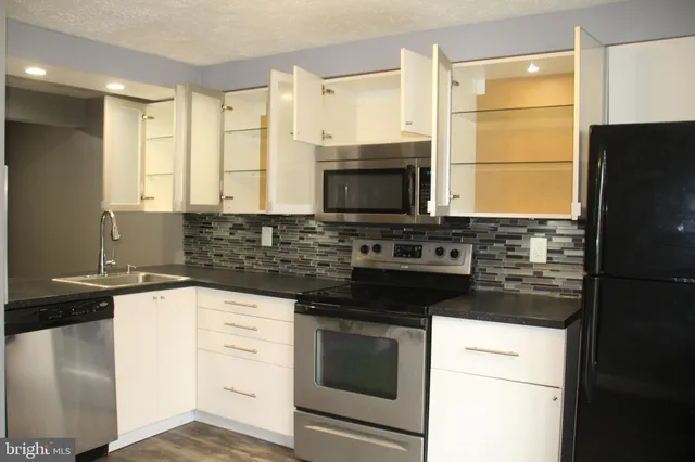 a kitchen with granite countertop a refrigerator stove and microwave