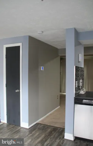 an empty room with wooden floor and kitchen view