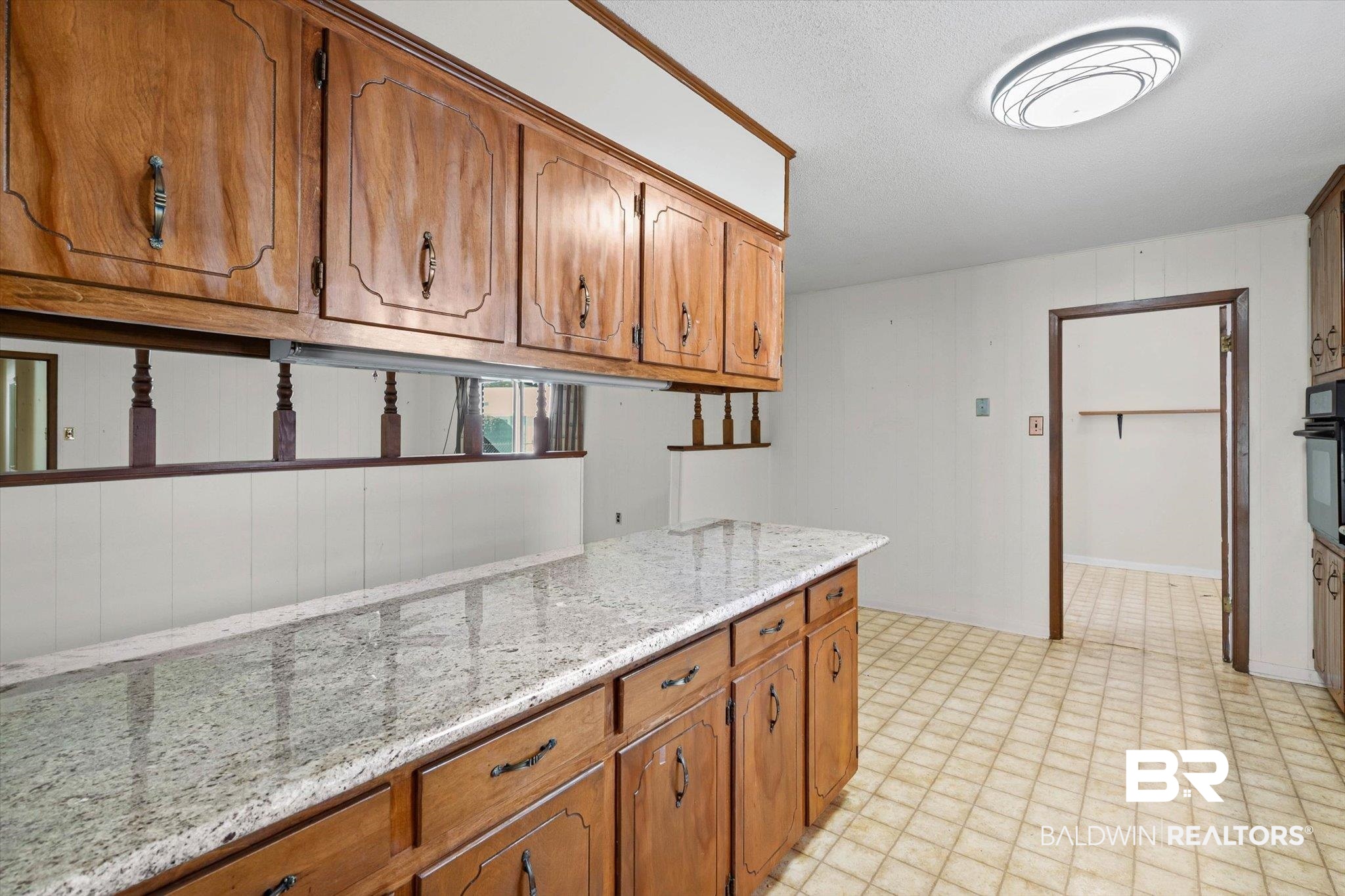 6300 Christopher Drive North Mobile, AL 36609 - Photo 6 of 22 Kitchen with brown cabinets, light stone counters, and oven