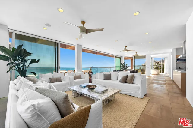 a living room with furniture kitchen view and a large window