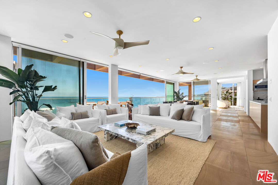 a living room with furniture kitchen view and a large window