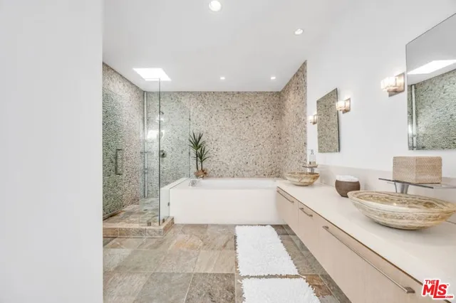 a bathroom with a tub a sink and a large mirror