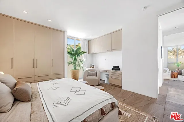 a bedroom with a bed a table and potted plant