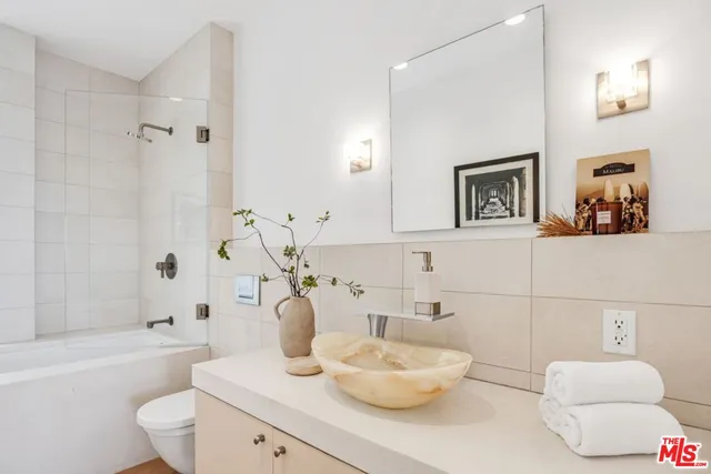 a bathroom with a bathtub sink vanity mirror and toilet