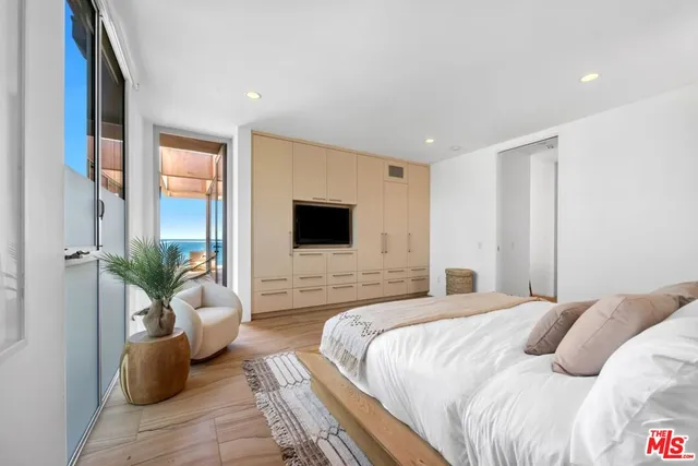 a bedroom with a large bed couch and a flat screen tv