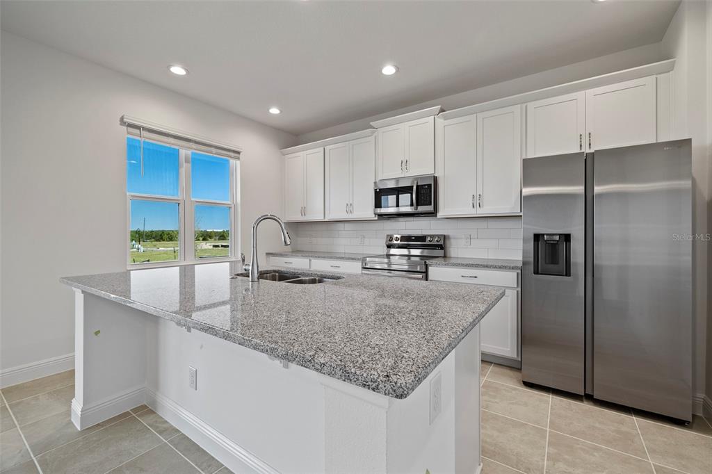 7120 Cherry Pasture Road Groveland, FL 34736 - Photo 6 of 23 a kitchen with stainless steel appliances granite countertop a refrigerator a sink a stove a microwave and island