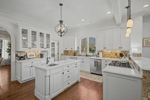 a kitchen with a stove a sink dishwasher a refrigerator and a dining table with wooden floor