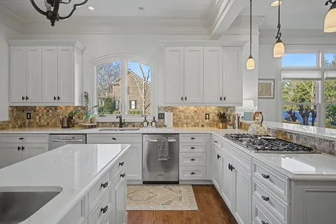 a kitchen with granite countertop a stove a sink dishwasher and white cabinets with wooden floor